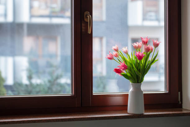 istock pink tulips in vase on windowsill 2078762942