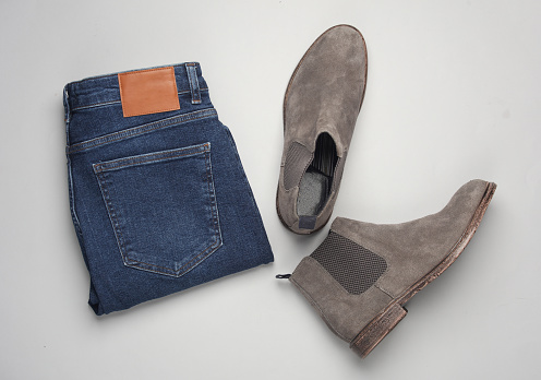 Blue jeans and chelsea boots on a gray background. Men's style. Top view. Flat lay