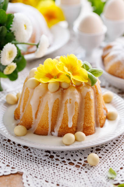 Bolo Bundt, Babka coberto com cobertura, decorado com ovos de chocolate e flores de prímula, close-up. - foto de acervo