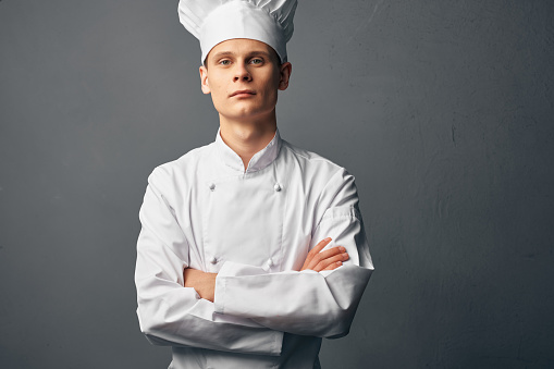 male chef in a white cap holds his hands in front of him self-confidence professionals. High quality photo