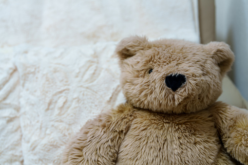 Cute little girl playing with teddy bear on bed