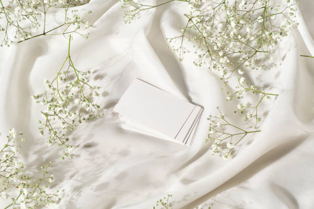 絹の白い布と花が描かれたテーブルの上の白い名刺