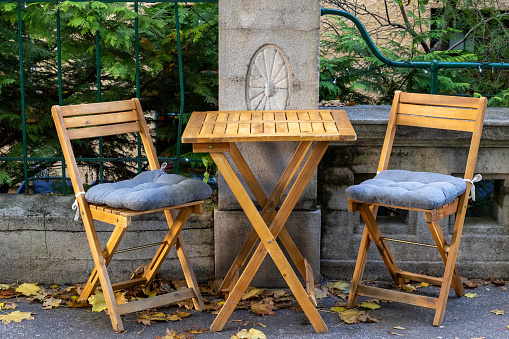 Two small foldable wooden chairs with cushions on sidewalk in front of a coffeehouse in Bratislava Old Town