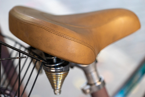 Close-up of artisanal vintage bicycle seat covered in fine leather with spring coil shock absorbers against blurred background for copy space