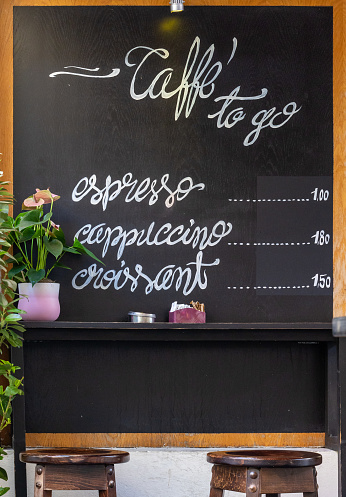 Handwritten words espresso, cappuccino and croissant on black chalkboard of European coffeehouse with prices