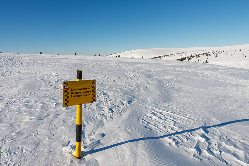 A sign warning of the avalanche area, white elbe valley, krkonose mountains, winter day. Avalanche area warning sign in czech, english and german language.