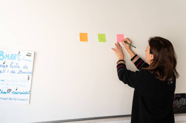 istock Happy mature teacher writing sticky notes in the classroom. 2078961944