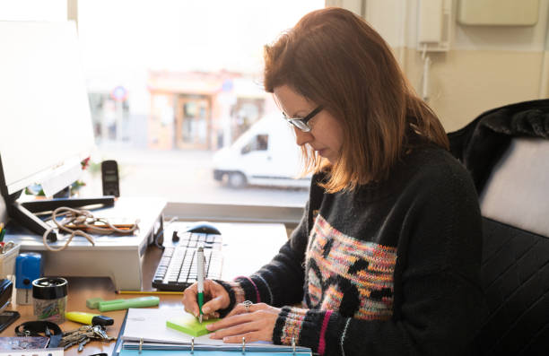 istock Woman writing notes on adhesive note in the office 2078963520