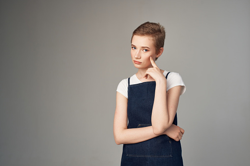 Pensive little schoolgirl sitting on panel isolated on white background