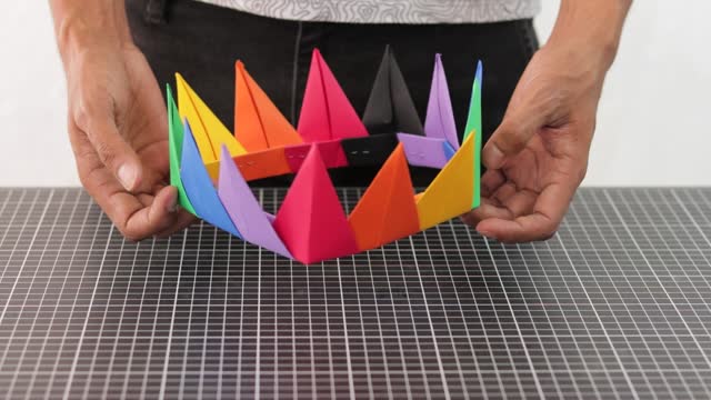 Hands showing colorful rainbow paper handmade crown, crafting