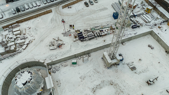 Drone photography of a construction site in a city covered by snow during winter cloudy day