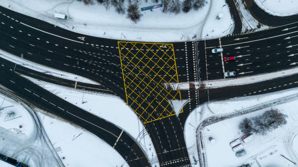 drohnenfotografie von draufsicht auf mehrspurige straßen, die sich an einem wintertag kreuzen - driving industry land vehicle multiple lane highway stock-fotos und bilder