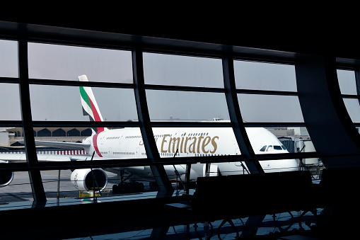 Al Garhoud district, Dubai: Emirates Airbus A380-842 (A6-EUM) at a passenger boarding bridge, seen from the terminal, with curved window frames - Dubai International Airport, terminal 3.