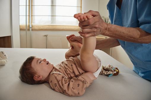 Little baby receiving chiropractic or osteopathic foot massage.