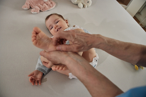 Little baby receiving chiropractic or osteopathic foot massage.
