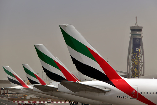 Al Garhoud district, Dubai: Dubai International Airport, terminal 3, the hub for Emirates - line of Emirates aircraft at gate position aling the terminal, with the control tower in the background. Boeing 777-300(ER) A6-EQP in the foreground.