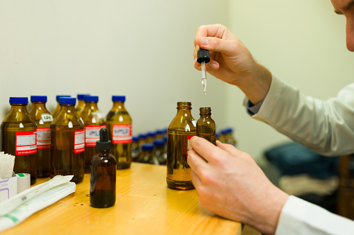 Doctor or therapist preparing the homeopathic formula and alternative medicine for his patients on homeopathy therapy