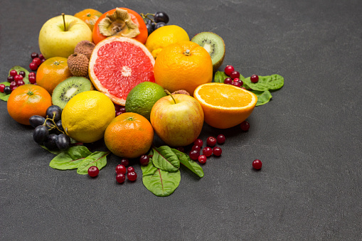 Set of varied, multicolored exotic fruits. Mandarins, grapefruit, lychee, kiwi and grapes with chard leaves. Black Background. Top view\nCopy space