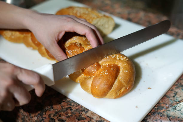 close up on person hand cutting bread by knife