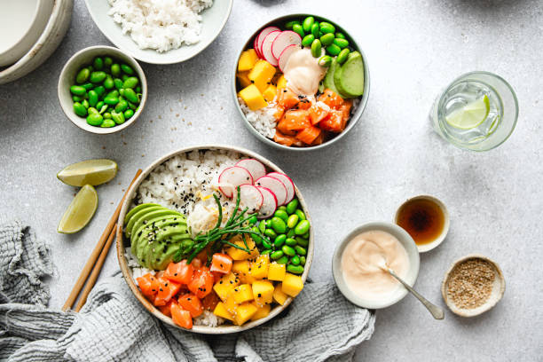 Top view of scrumptious poke bowl with salmon Top view of scrumptious poke bowl with salmon. High angle view of salmon poke salad placed on the kitchen table for dinner. fish in a bowl stock pictures, royalty-free photos & images