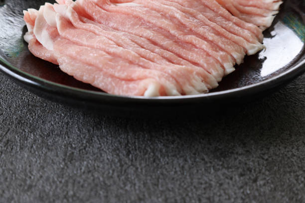 istock Thinly sliced raw pork on a black crockery isolated on a gray background. 2079072381