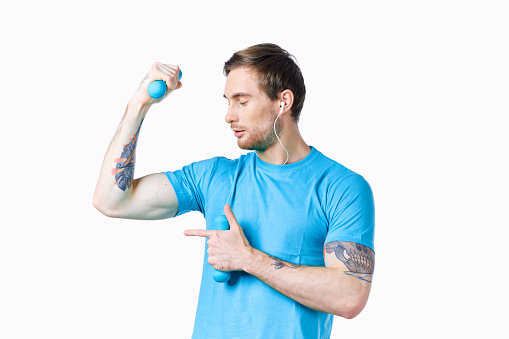 man with dumbbells pumped up arm muscles smile model tattoo blue t-shirt. High quality photo