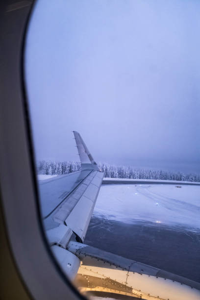 Airplane window scene while taking off on a snowy white track airport landscape