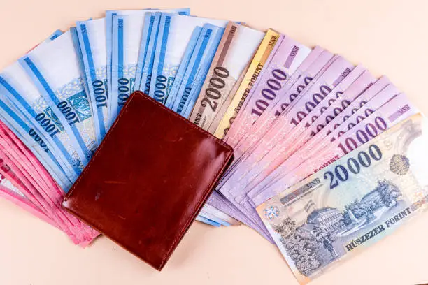 Hungarian HUF banknotes spread out and leather wallet on a yellow background