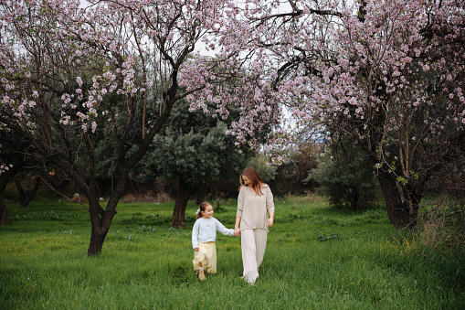 Loving mom playing outside with her daughter. Happy young father and daughter having fun while running in spring day at the park.