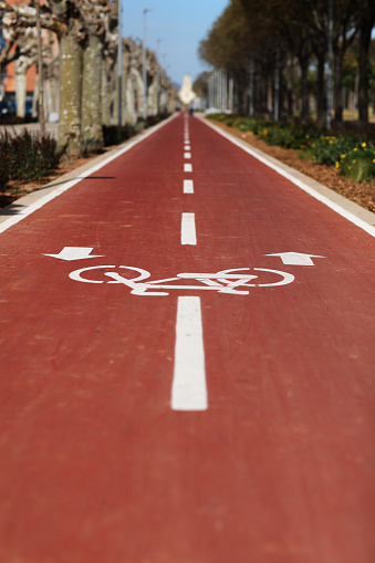 New marking bike path. White bicycle symbol and two oposite arrows on red asphalt lane, road. Bicycle path in the city. Two-way cycle lane on an avenue. Lifestyle. Urban traffic and transportation.