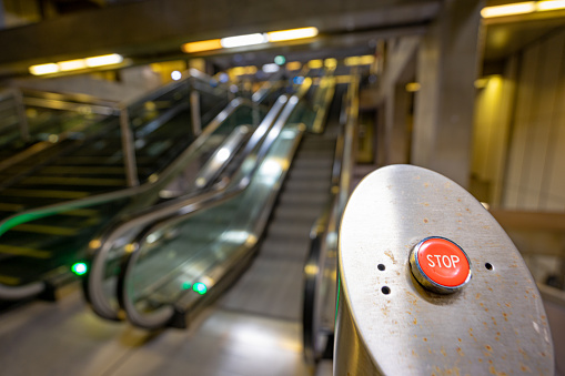 red STOP button to turn off the movement of escalators on a subway station platform.