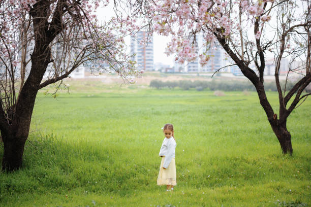 Little girl taking a walk all alone in a park or forest. Cute girl running on the road in the park on a sunny day. Family time. Blooming trees