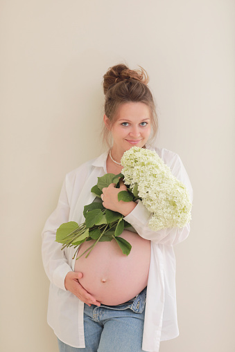 healthy pregnancy. Side view pregnant woman with big belly advanced pregnancy in hands. girl holding big bouquet of flower. copy space for text. Elegant mother waiting baby. selective focus