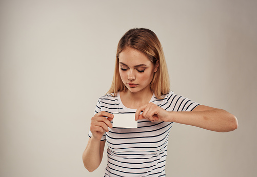 Pretty woman in a striped T-shirt with a business card in her hand. High quality photo