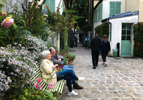 Paris, France: A senior couple sitting in the cobbled courtyard of La Musée de la Vie Romantique in the Pigalle district of the 9th arrondissement; the literary museum focuses on George Sand and other authors of the Romantic Era.