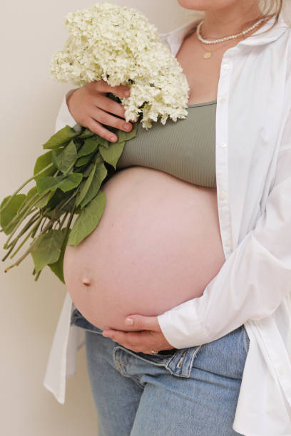 healthy pregnancy. side view pregnant woman with big belly advanced pregnancy in hands. girl holding big bouquet of flower. copy space for text. elegant mother waiting baby. selective focus. - mothers day mother single flower family stock-fotos und bilder