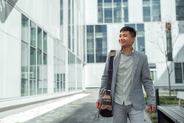 istock Well dressed young businessman walking in front of modern building 2079245361