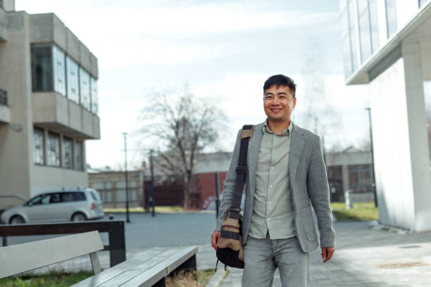 istock Well dressed young businessman walking in front of modern building 2079245362