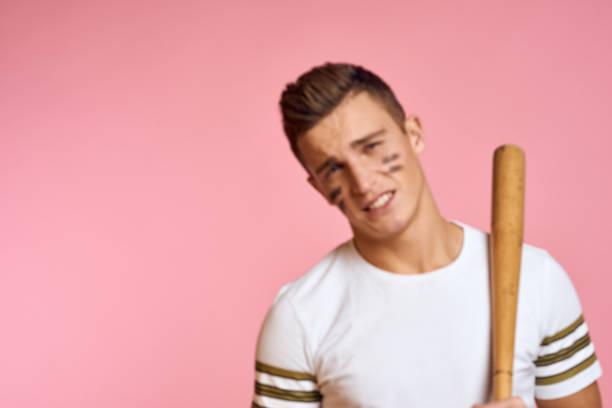 istock Energetic man with a bat on a pink background T-shirt face make-up black lines aggression model 2079300029