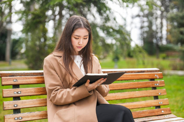istock Asian woman sitting on bench in university campus studying 2079320356