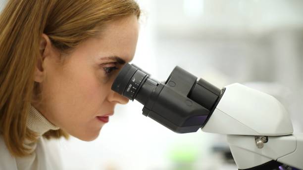istock Close-up of caucasian woman looking through a microscope 2079346374