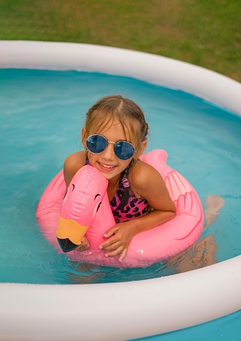 A child swims in a mini inflatable swimming pool with a pink circle in the shape of a flamingo.