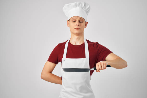 chef in uniform Frying pan in the hands of a professional restaurant kitchen