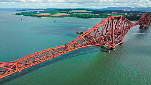 Aerial view of Forth Bridge, a long red railway bridge crossing the Forth estuary.