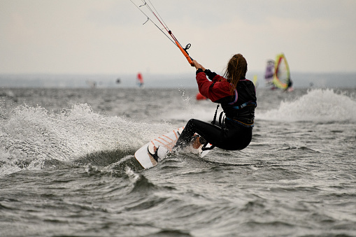 Group of people doing kitesurfing and windsurfing on sea.