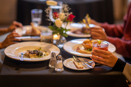 A small group of four adults sit together in a restaurant as they enjoy a meal together.  They each have a dish out in front of them in this view of their table.