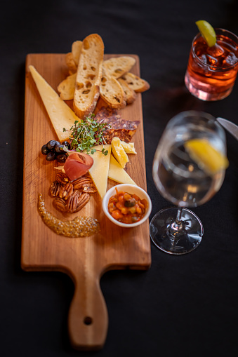 A beautiful Charcuterie board spread is sitting in the middle of a table as a small group of adults enjoy a night out together.