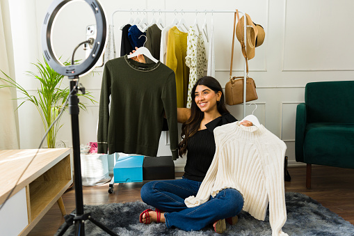 Young woman seated with trendy clothes, engaging with viewers through a live stream