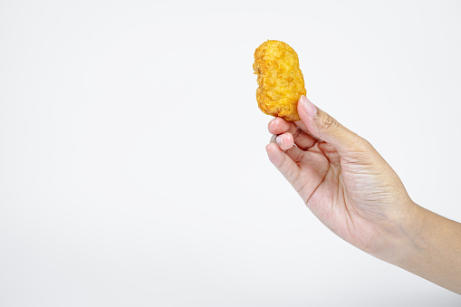 Female hand is holding fried chicken nuggets on white background.