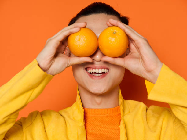 istock smiling man with orange oranges over isolated background and yellow jacket 2079463827